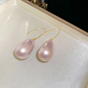Macro detail view of elegant pink teardrop earrings with long golden hooks on silk