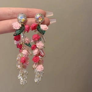 Close-up of pink floral and crystal tassel earrings in a romantic vacation style