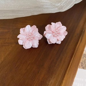 Exquisite pink blooming flower stud earrings with pearl centers on rustic wood background