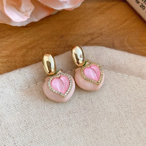 Detail view of sweet pink peach stud earrings with rhinestone borders and gold accents.