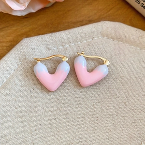 Close-up detail of stylish pink and white heart drip enamel earrings with gold hoops
