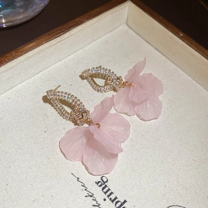 Close-up detail of elegant pink petal earrings with pavé crystal studs on fabric tray