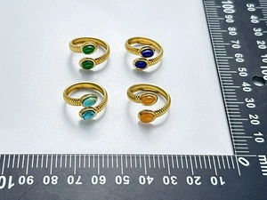 Detailed view of four ribbed 18K gold stainless steel rings with colorful gemstones