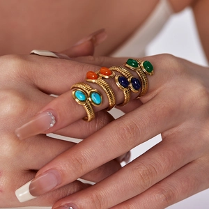 Close-up of four stacked gold spiral rings with turquoise and lapis oval gemstones