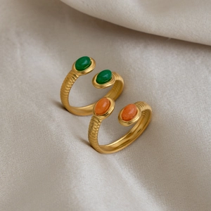 Macro detail of 18K gold stainless steel open ring with green and orange gemstones
