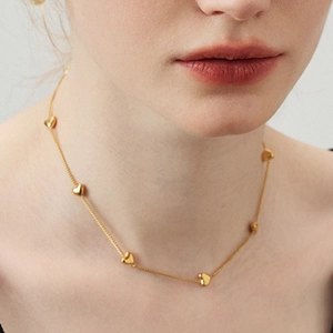 Gold minimalist heart pendant necklace on female model neck in a close-up view