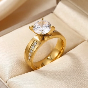 Close-up detail of a minimalist gold stainless steel ring with a brilliant four-prong set stone