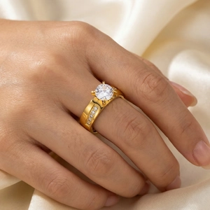 Close-up of a gold stainless steel four-prong diamond ring on a model's finger