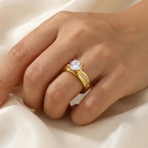 Close-up of gold-plated four-prong diamond ring on a hand with satin background.