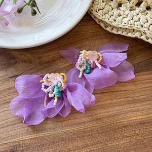 Dettaglio orecchini a fiore in chiffon viola con nappe di perline colorate e argento