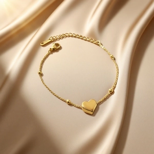 Bracelet cœur en or 18 carats avec perles sur fond en satin de couleur champagne