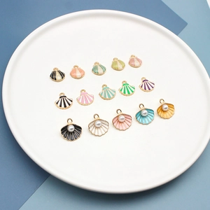Kleurrijke zeeschelp bedeltjes met parels op een wit bord voor DIY sieraden maken.