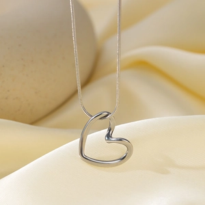 Hollow heart pendant necklace in silver stainless steel on soft silk background