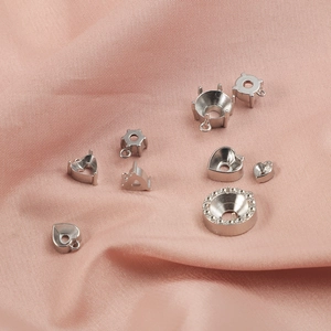 Nahaufnahme von herzförmigen und runden Edelstahl-Krallenfassungen für DIY-Schmuck.