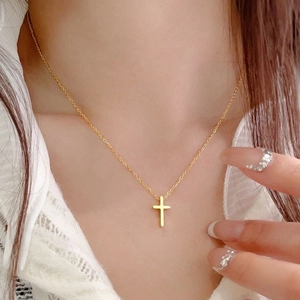 Nahaufnahme einer eleganten 18k Gold-Kreuzkette, getragen von einem Modell