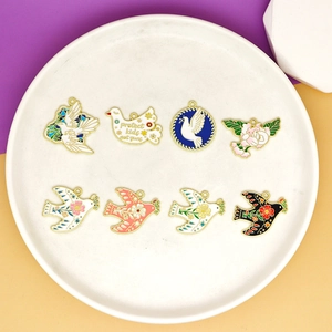 Detail view of assorted peace dove enamel charms with floral patterns and slogans