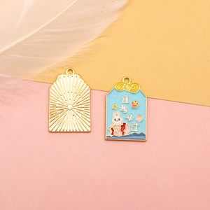 Detailed view of lucky blue Omamori alloy charms featuring rabbit and koi fish patterns