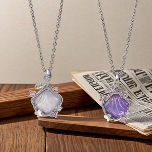 Close-up of shell pendant necklace with white and purple inlay and zircon stones