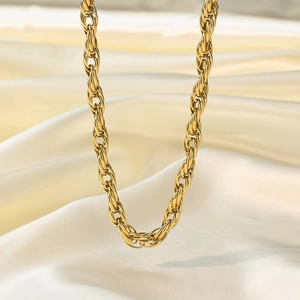 Élégant collier chaîne torsadée dorée présenté sur un fond de tissu en satin blanc