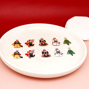 Collectie kerstbedeltjes van emaille met zwarte katten op een witte keramische plaat.
