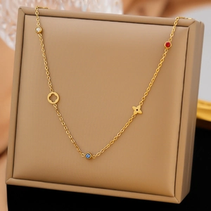 Goldene Edelstahlkette mit Kleeblatt-Anhängern und bunten Edelsteinen auf einem Display