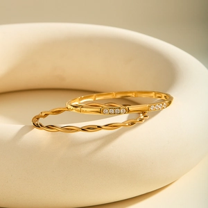 Dettaglio di bracciali rigidi in acciaio inossidabile placcato oro 18k a treccia e con cristalli
