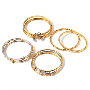 Dettaglio di bracciali rigidi impilabili in acciaio inox con ciondoli a cuore e intrecci.