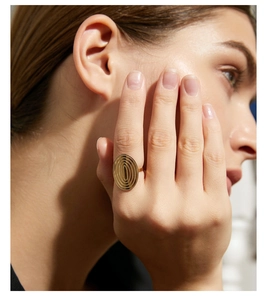 Detailansicht eines ovalen goldenen Edelstahlrings mit Textur am Finger des Modells