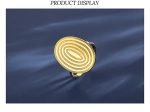 Detail eines strukturierten goldenen Ovalrings mit konzentrischen Kreismustern auf Stoff