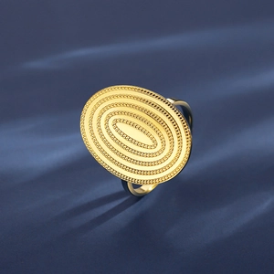 Golden textured oval ring with concentric circles and beaded design on dark blue background