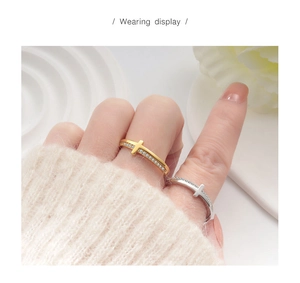 Close-up of gold and silver cross rings with zircon stones worn on fingers