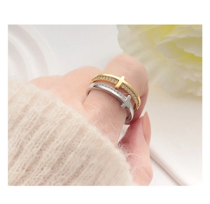 Detailed close-up of gold and silver cross rings with cubic zirconia on female hand
