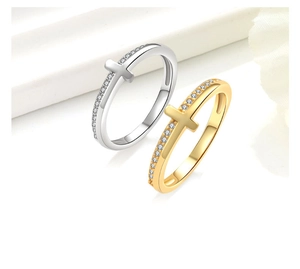 Close-up of gold and silver cross rings featuring delicate pave-set cubic zirconia stones