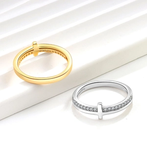 Minimalist 18K gold and silver cross rings with pavé diamonds on a white platform