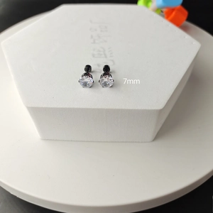 Detailed close-up of 7mm round zircon stud earrings with black claw setting on white stand