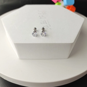 Macro shot of silver titanium steel stud earrings with round-cut zircon on white base