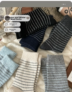 Detail of wool blend striped socks in six colors laid on a cozy white blanket