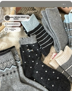 Detailed view of gray and blue wool socks with patterns on a soft white knit blanket