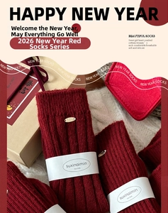 Detailed view of red festive wool socks with ribbed knit texture and white gift packaging