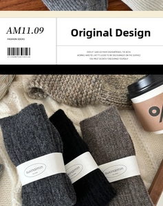 Close-up of thick cable knit wool socks in dark grey with suxinaimin brand packaging
