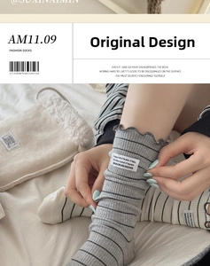 Detail of grey striped crew socks featuring ruffle trim and embroidered cloth tag