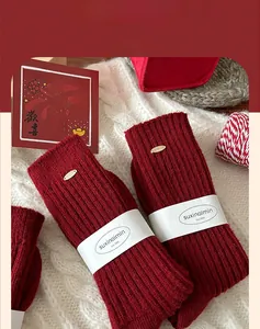 Macro shot of red knit fingerless gloves with vertical stripe texture and gold brand logo