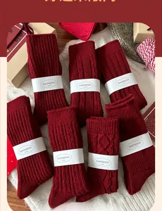 Set of seven red wool socks with various knit textures and gift packaging for New Year