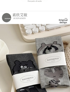 Detailed view of light and dark grey cotton socks with cute cartoon raccoon patterns