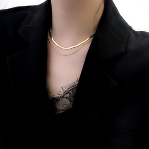 Macro view of layered gold herringbone chain and minimalist necklace on a model