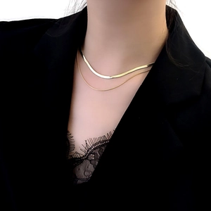 Close-up of double-layer gold snake chain necklace worn on neck with black outfit