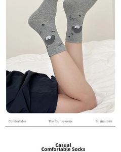 Macro view of light grey mid-calf socks with cute cartoon dogs and bow patterns