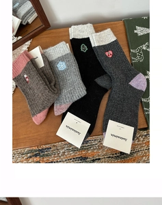 Detailed close-up of winter wool socks featuring festive Christmas embroidery and rib cuffs