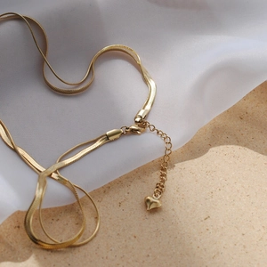 Detail of gold double-layered snake chain necklace with lobster clasp and heart pendant