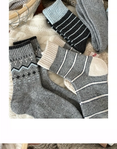 Close-up of thick knitted wool socks with snowflake patterns on a cozy white blanket